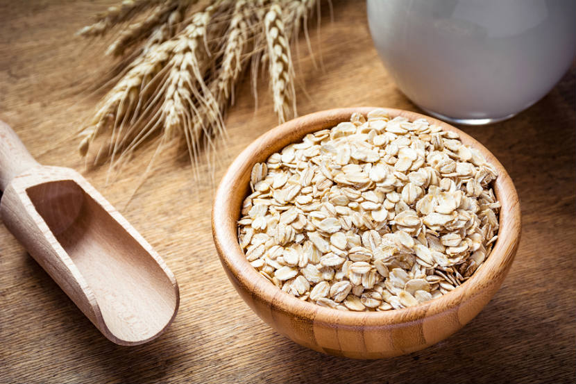 wooden bowl with oats in it with wheat on the table
